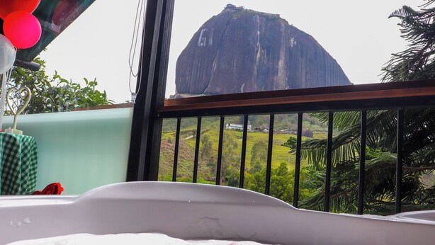 A bathtub with a view of a large rock formation and greenery. - Lakeview Cabin with Jacuzzi in Guatapé (Guatapé)