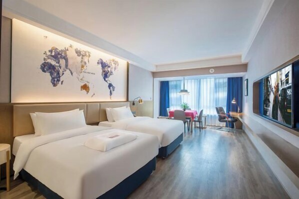 Ein Hotelzimmer mit zwei Betten, einer Weltkarte an der Wand, einem Essbereich mit Tisch und Stühlen sowie einem großen Fenster mit Vorhängen.