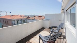 A balcony with two chairs, a view of buildings, and a construction crane in the background. - Liiiving in Porto - Downtown Balcony Apartment (Porto)