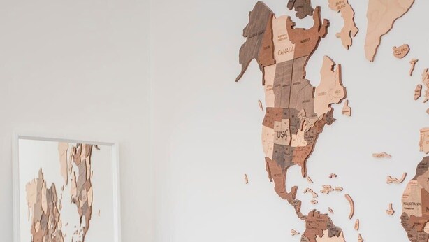 A room with a large wooden map of the world on the wall and a mirror on the floor. - Liiiving in Porto - Downtown Balcony Apartment (Porto)