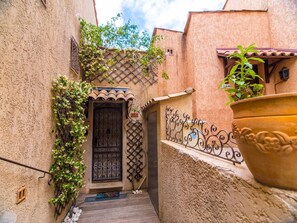 Stucco-clad building with a tiled roof and wrought iron gate leads to a charming entrance.