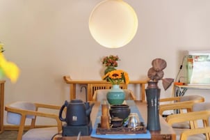 Ein Essbereich mit Tisch für zwei Personen, einer Blumenvase und einer großen Leuchte darüber.