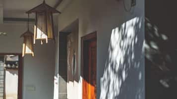 A hallway with hanging lanterns, a wooden door, and a wall with a shadow pattern.