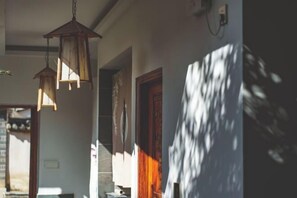 A hallway with hanging lanterns, a wooden door, and a wall with a shadow pattern. - Huachengju View Guesthouse (Jianshui)