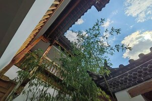 Un edificio tradicional con tejado de tejas y una planta de bambú en primer plano.