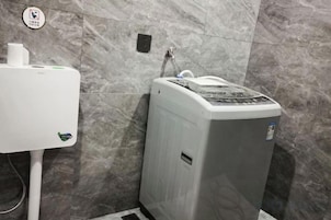 Casa de banho com esquentador, sanita e tomada elétrica na parede.