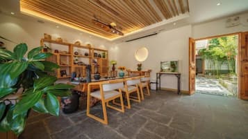 A dining area with a wooden table and chairs, surrounded by shelves with various items.