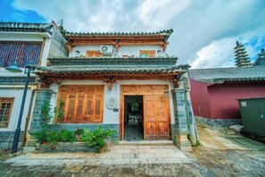 A traditional Chinese building with a wooden gate, a tiled roof, and a stone base. - Huachengju View Guesthouse (Jianshui)