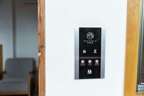 A sign with Chinese characters and symbols on a wall, indicating a room or area in a building. - Huachengju View Guesthouse (Jianshui)