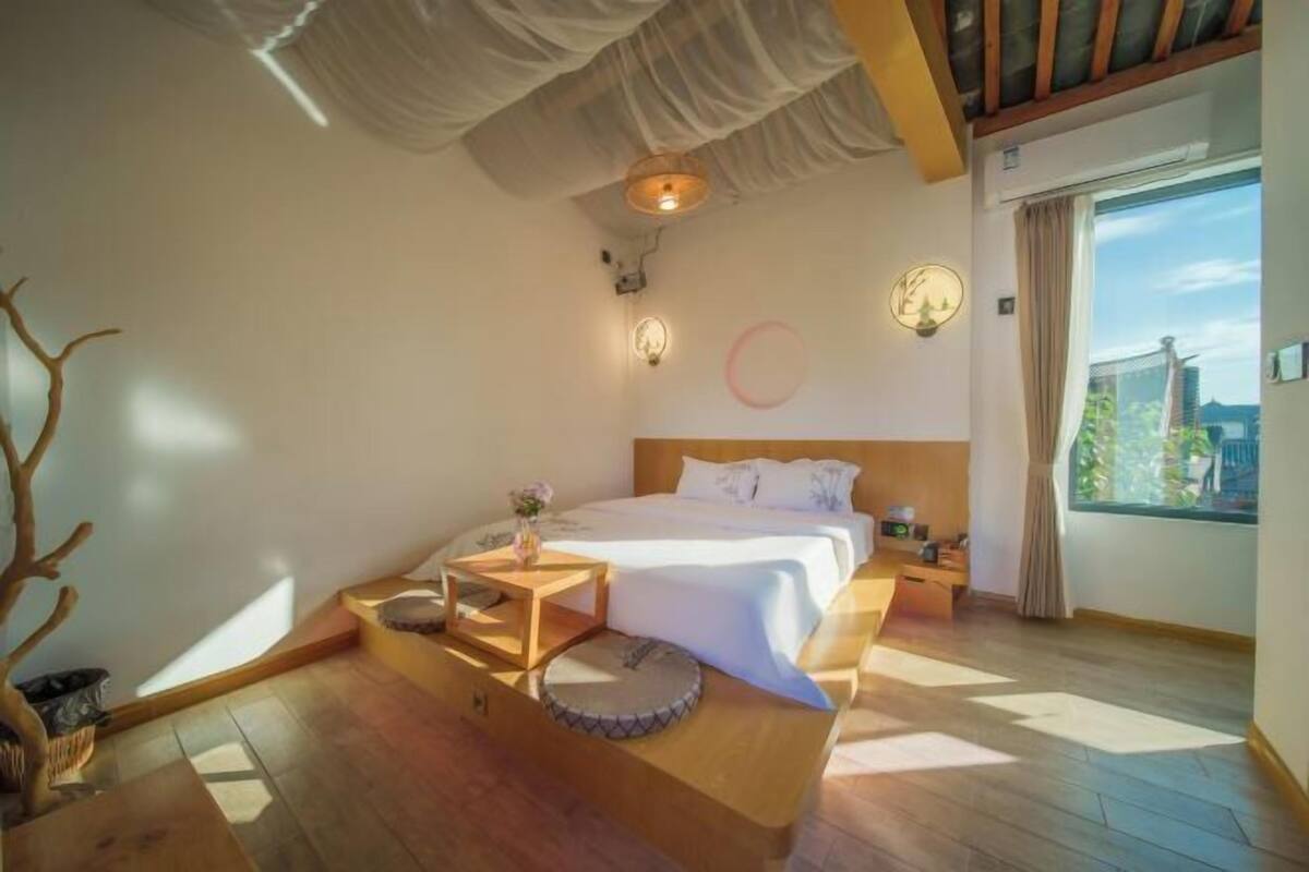 A bedroom with a bed, bedside tables, a nightstand, a window with a view, and a ceiling with a light fixture.