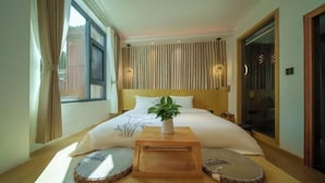 A neatly arranged bedroom with a bed, bedside tables, a potted plant, and a window with curtains. - Huachengju View Guesthouse (Jianshui)