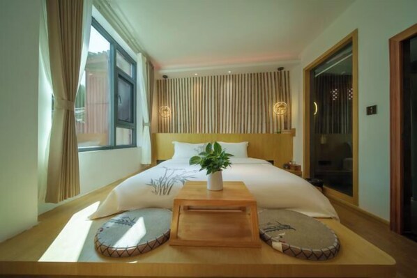 A neatly arranged bedroom with a bed, bedside tables, a potted plant, and a window with curtains. - Huachengju View Guesthouse (Jianshui)