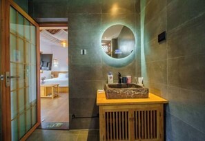 A traditional Japanese-style room with tatami flooring, a wooden cabinet with a mirror, and a sliding door leading to a bedroom.