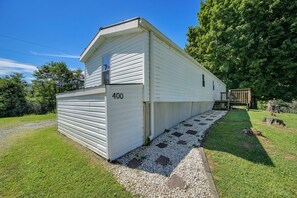 A mobile home with a number 400 on the side, a small porch, and a gravel pathway leading to the entrance. - Pet friendly, hdtv°Fireplace°Netflix°Backyard (Deep gap)