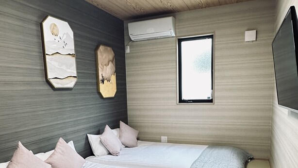 A bedroom with two beds, a wooden ceiling, a skylight, a mounted air conditioner, and a window. - Tabitime tengachaya  (Osaka)