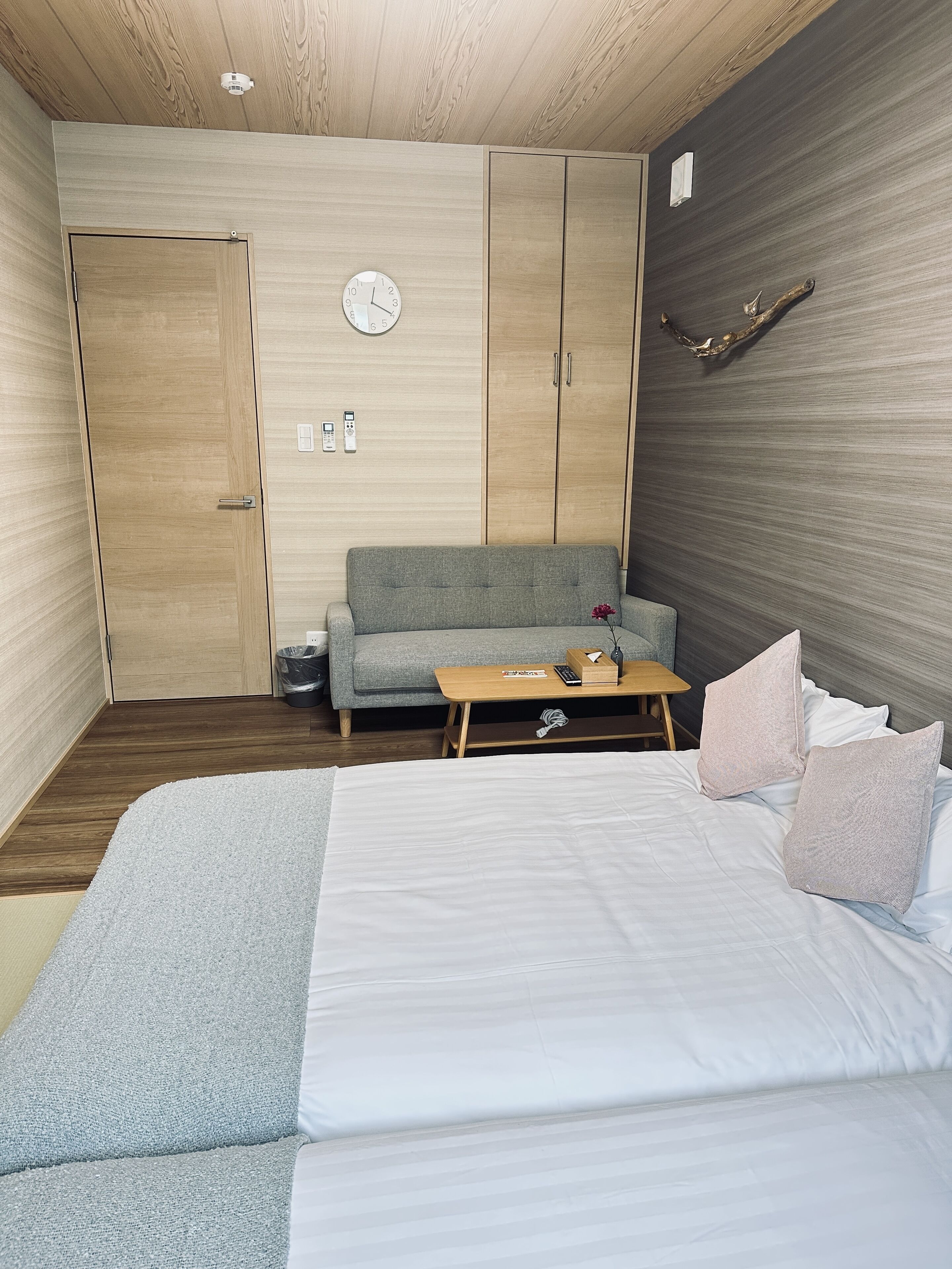 A bedroom with a bed, a sofa, a wooden table, and a wardrobe.
