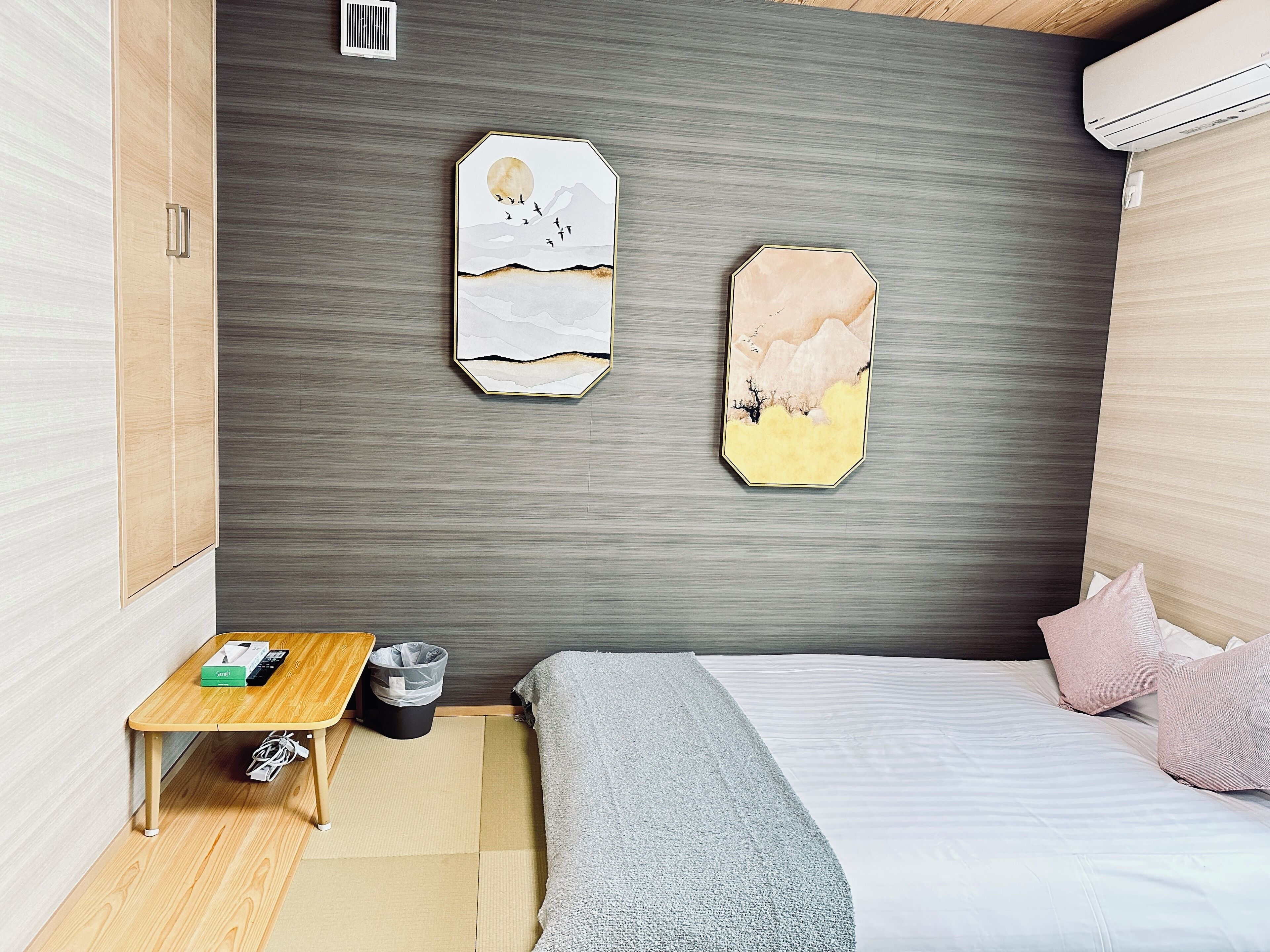 A compact bedroom with a bed, a small table, and two wall art pieces.