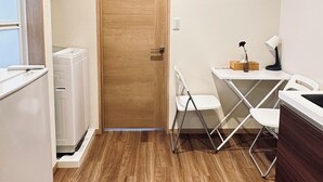 A compact kitchen with a wooden door, a small table with chairs, and a refrigerator. - Tabitime tengachaya  (Osaka)