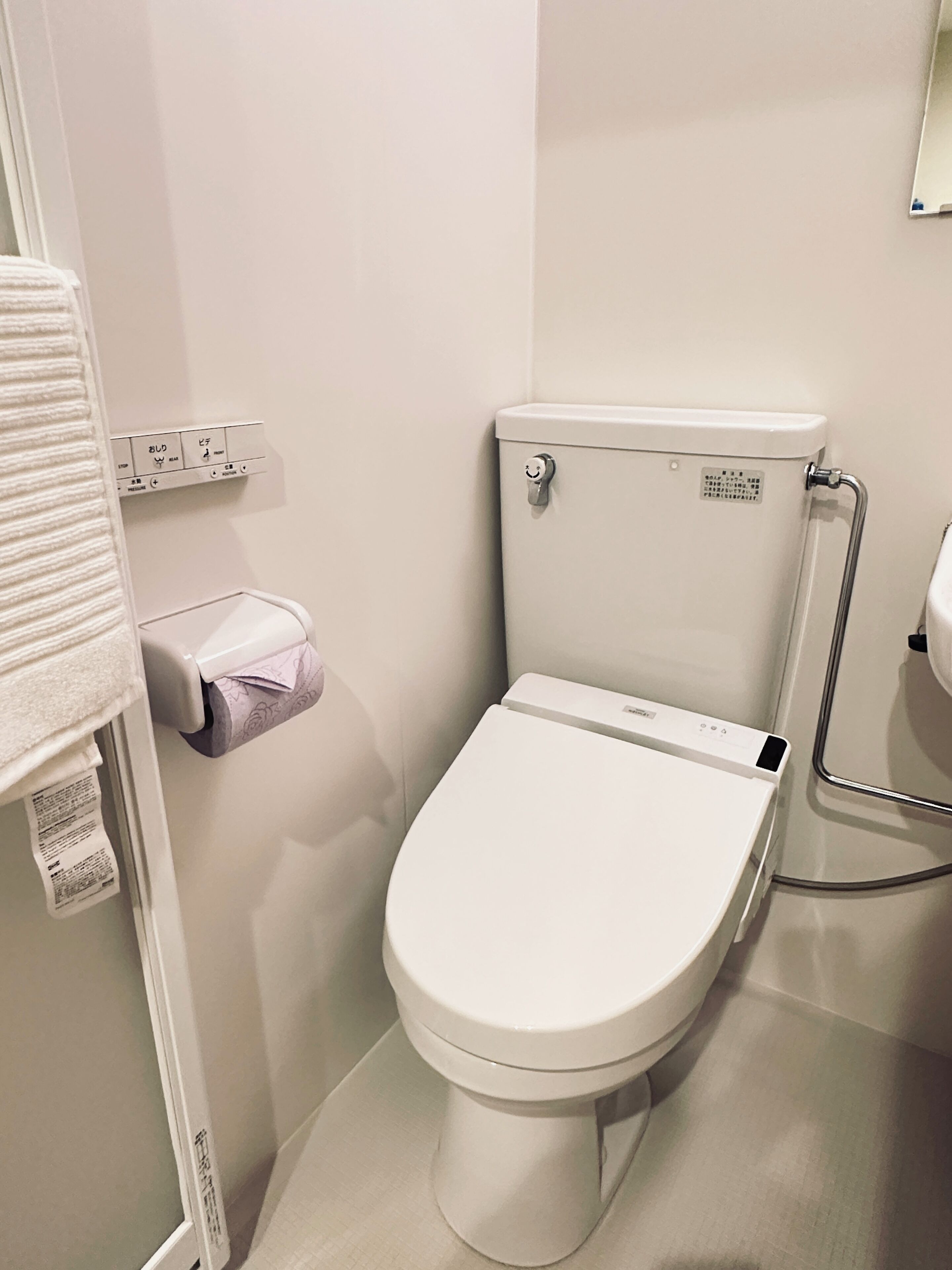Des toilettes modernes dotées d’un panneau de commande, d’un porte-rouleau de papier toilette et d’une barre d’appui.