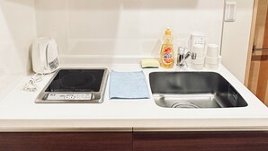 A compact kitchenette with a built-in stove, a sink, and a microwave. - Tabitime tengachaya  (Osaka)