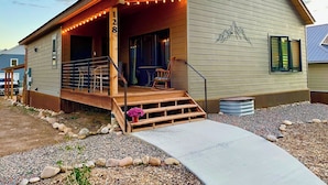 Einbungalow mit Veranda, Holzstufen und einem kleinen Garten mit Kies und Steinen.