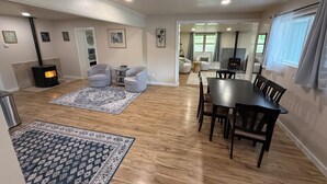 A spacious living area with a fireplace, two armchairs, a dining table, and a patterned rug. - Pool Table, Hot Tub! 5 bedroom, 3 bath, 5 min to Cal Poly or Old Town. (Eureka)