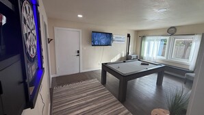 A billiards table with a pool cue and balls, a television mounted on the wall, and a door with a blue-lit clock. - Pool Table, Hot Tub! 5 bedroom, 3 bath, 5 min to Cal Poly or Old Town. (Eureka)