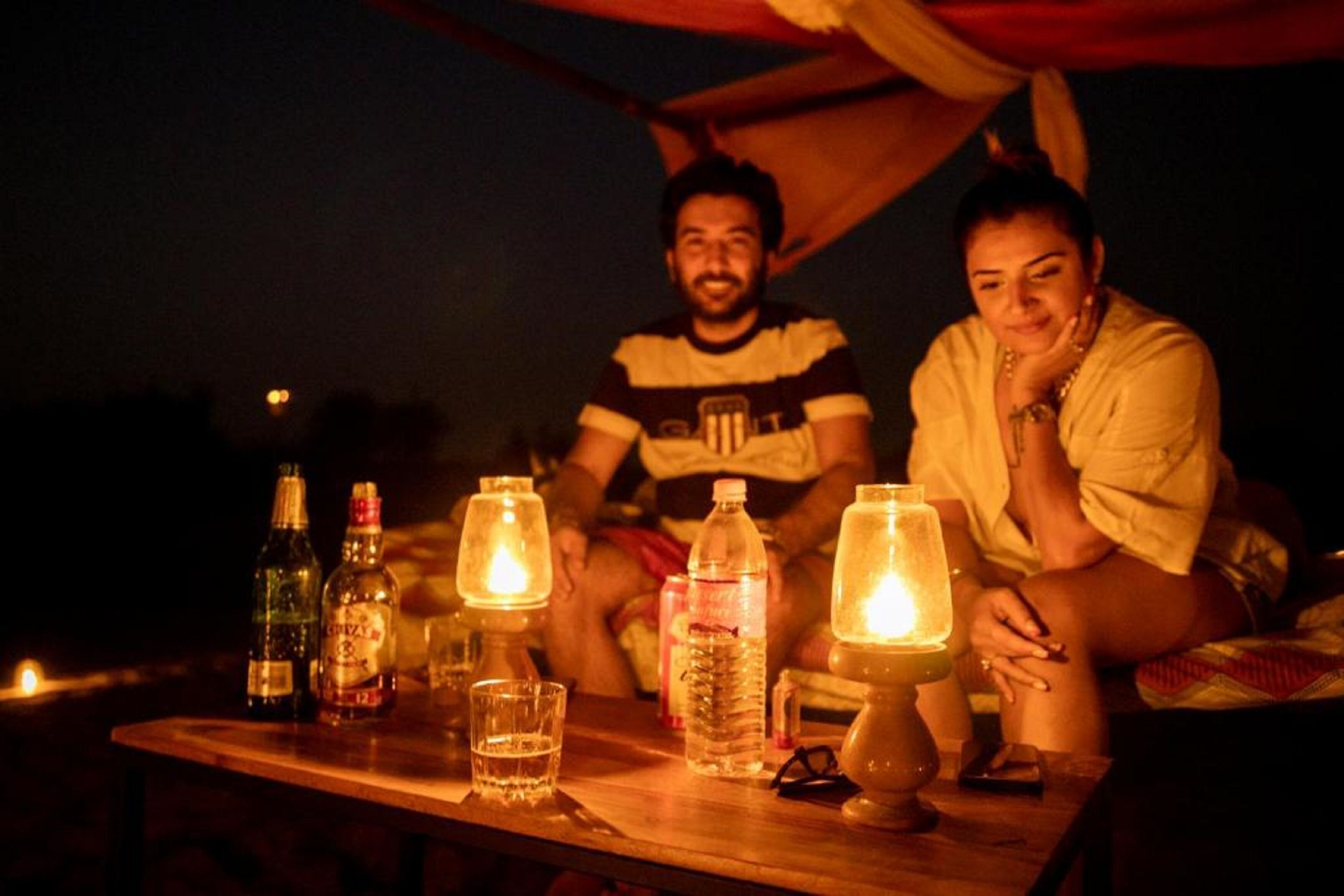 A tent with a table set up inside, featuring bottles, glasses, and a candle.