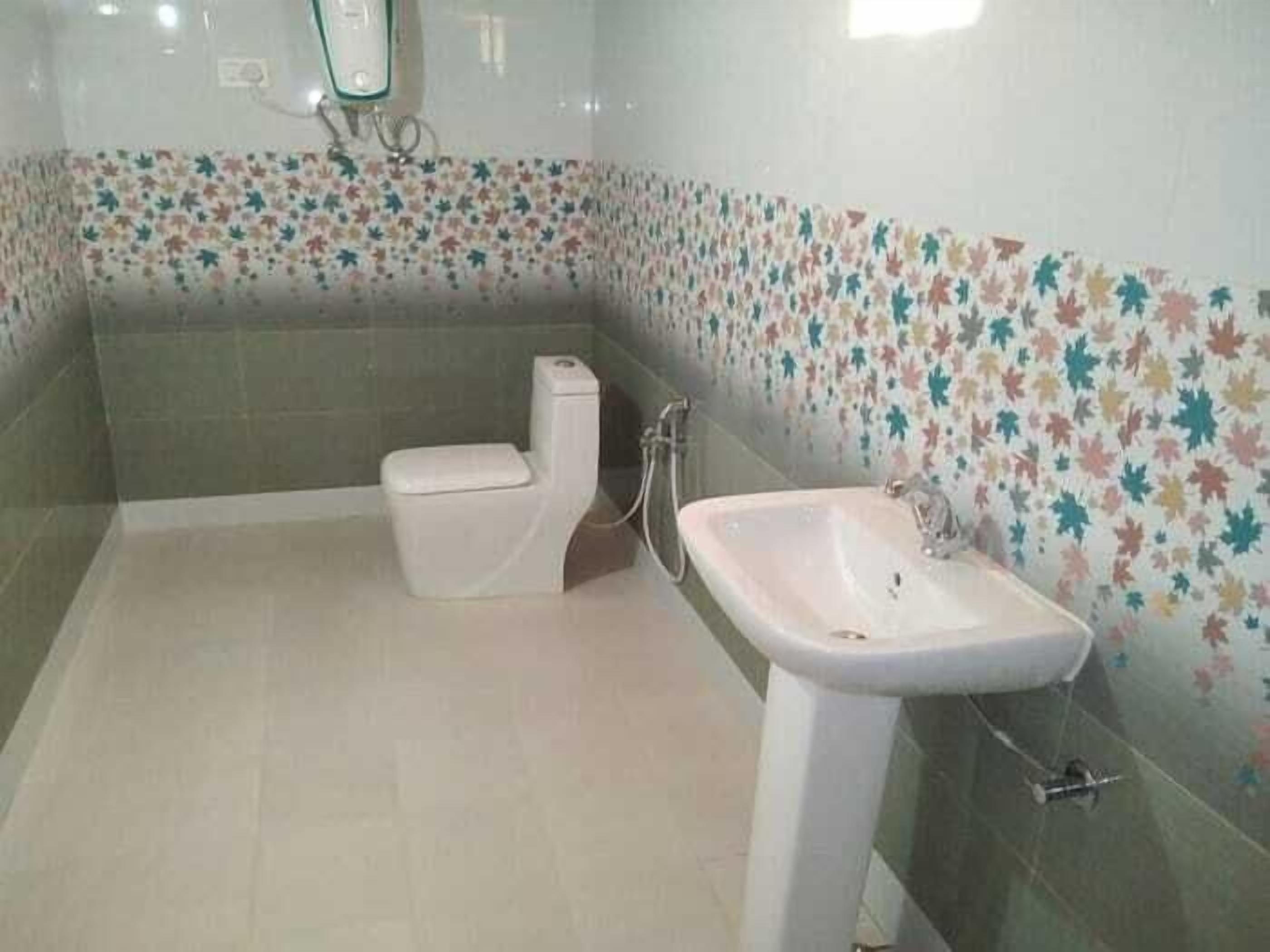 A bathroom with a toilet, sink, and tiled walls.