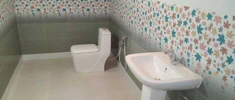 Un baño con inodoro, lavabo y paredes con azulejos.