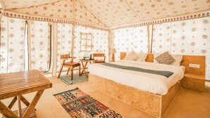 A tent-style room with a bed, a small table, and a chair. - Ozaki Desert Camp Jaisalmer (Jaisalmer)