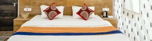 Restful retreat with a neatly made bed, wooden headboard, and a nightstand with a lamp and cup.