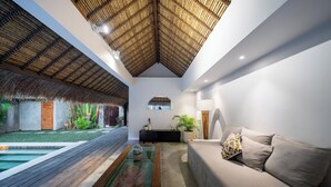A modern interior with a pool, a sofa, and a thatched ceiling.
