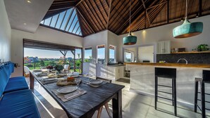 A modern kitchen with a large island, wooden ceiling, and pendant lighting.