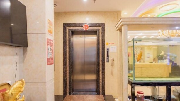 An elevator with a marble floor leading to a glass display case.