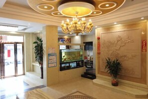 Un hall d'hôtel agrémenté d'un lustre, d'un comptoir de réception et d'un mur décoratif.