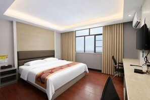 A hotel room with a bed, a desk, a chair, a TV, and a window with curtains. - Carlos Hotel (Kaiping Dongjiao Store) (Kaiping)