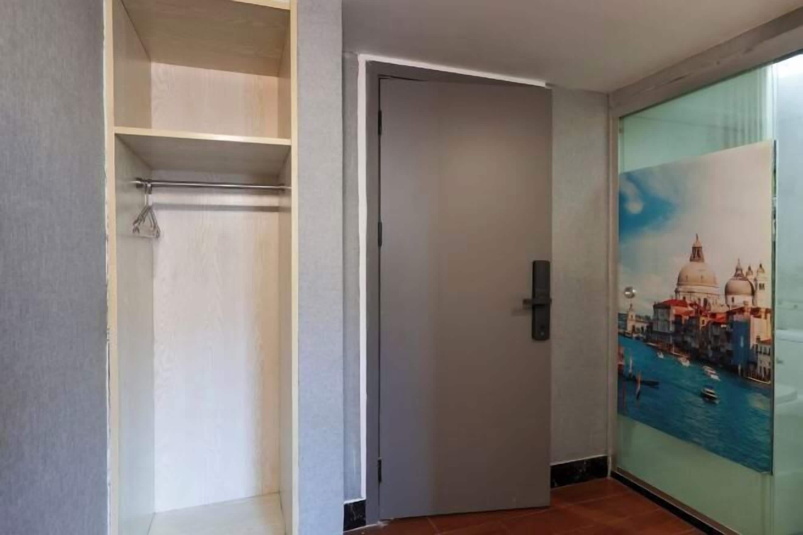 Una habitación con una puerta, un armario con repisas y una pared con un cuadro.