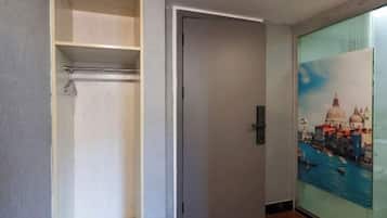 Una habitación con una puerta, un armario con repisas y una pared con un cuadro.