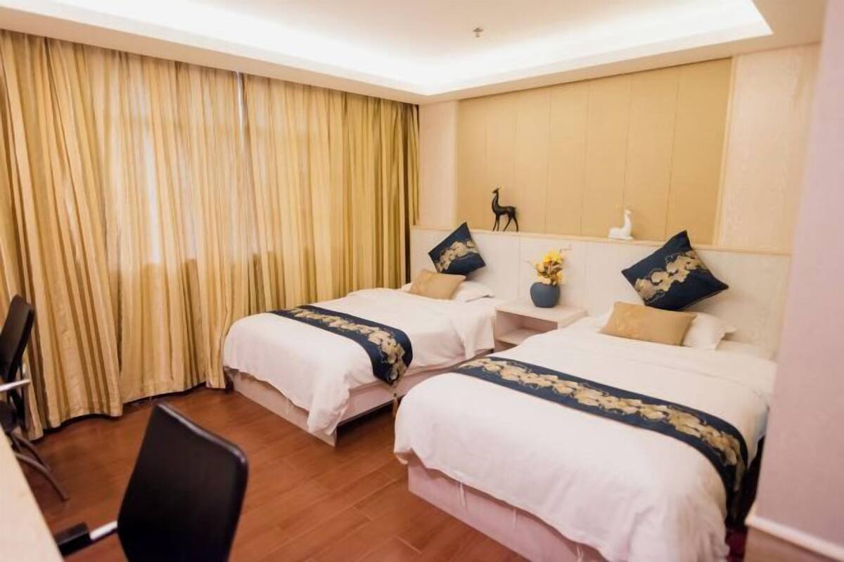 A hotel room with two beds, a desk, and a chair.