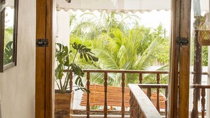 A room with a sliding glass door leading to a balcony with a wooden railing and a view of lush greenery. - CASA DE PLAYA FRENTE AL MAR CON JACUZZI  (Cartagena)