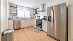 Una cocina moderna con electrodomésticos de acero inoxidable, suelo de madera y armarios blancos.