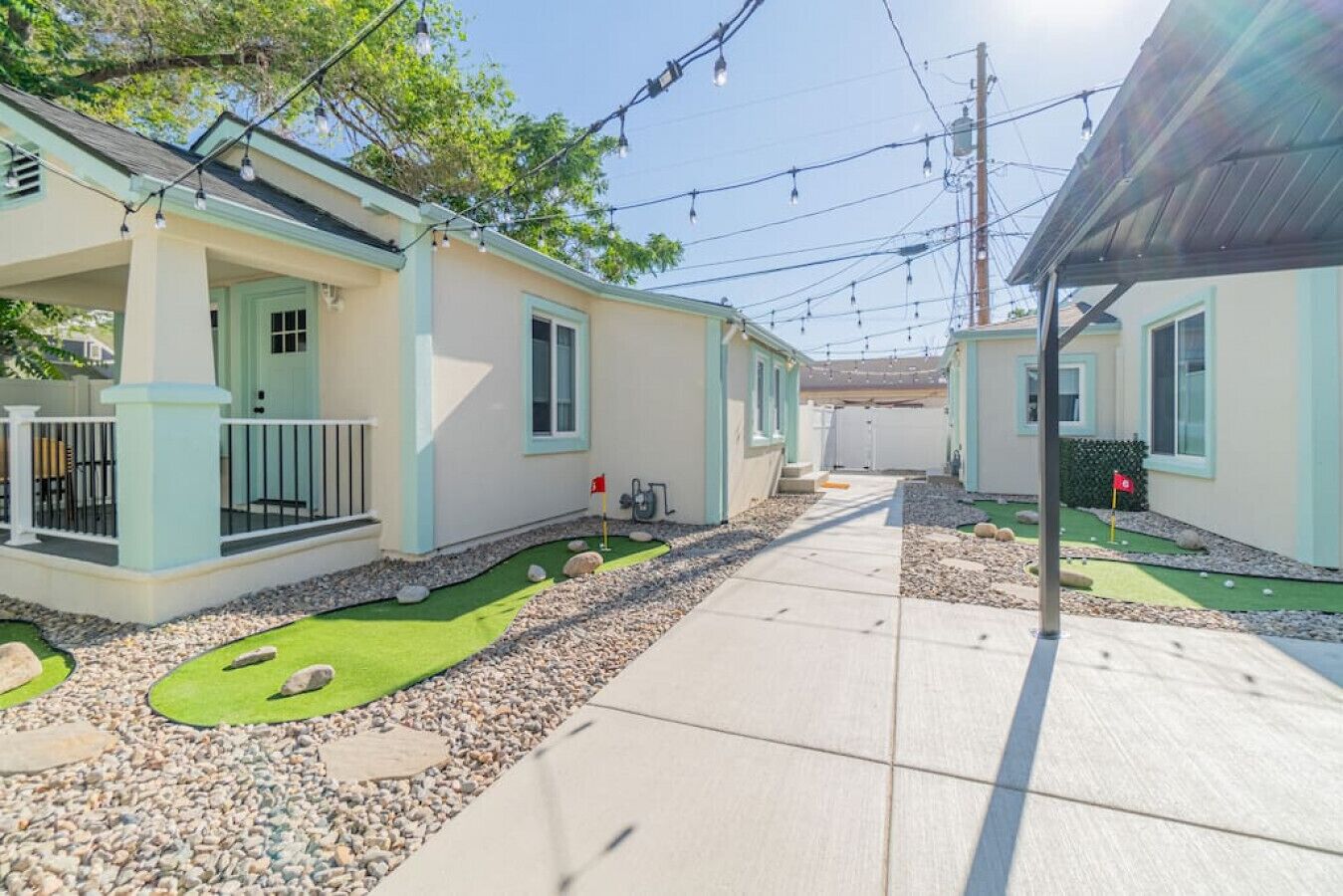 A row of two-story houses with a paved walkway and a small artificial green lawn.