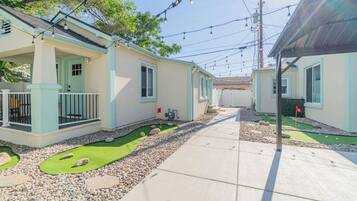 A row of two-story houses with a paved walkway and a small artificial green lawn.
