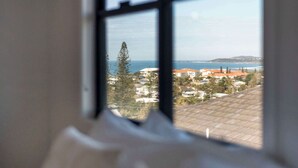 Une vue par la fenêtre sur une zone côtière, avec des bâtiments et un ciel dégagé.
