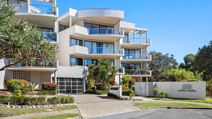 A multi-story hotel with balconies, a landscaped garden, and a sign indicating the name 'Costa Bella'. - Pristine 2-Bed Apartment with Pool and Balcony (Sunrise Beach)