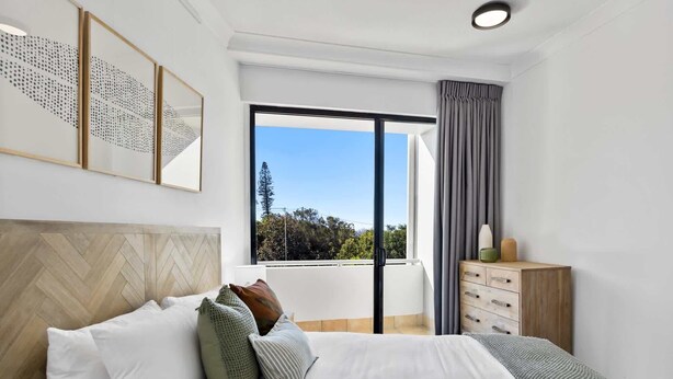 Une chambre à coucher avec un lit, une commode, une fenêtre donnant sur un beau paysage et un luminaire au plafond.