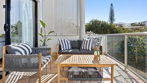 Un balcon aménagé avec un canapé, des chaises et une table, donnant sur un quartier résidentiel.