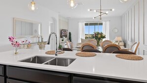 A modern kitchen with a central island, stainless steel sink, and pendant lighting.