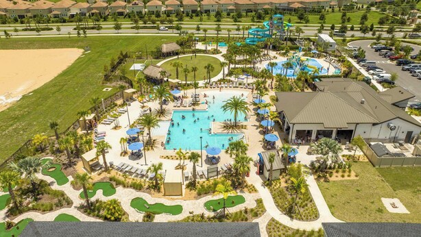 An aerial view of a resort with multiple swimming pools, a water park, and a golf course.